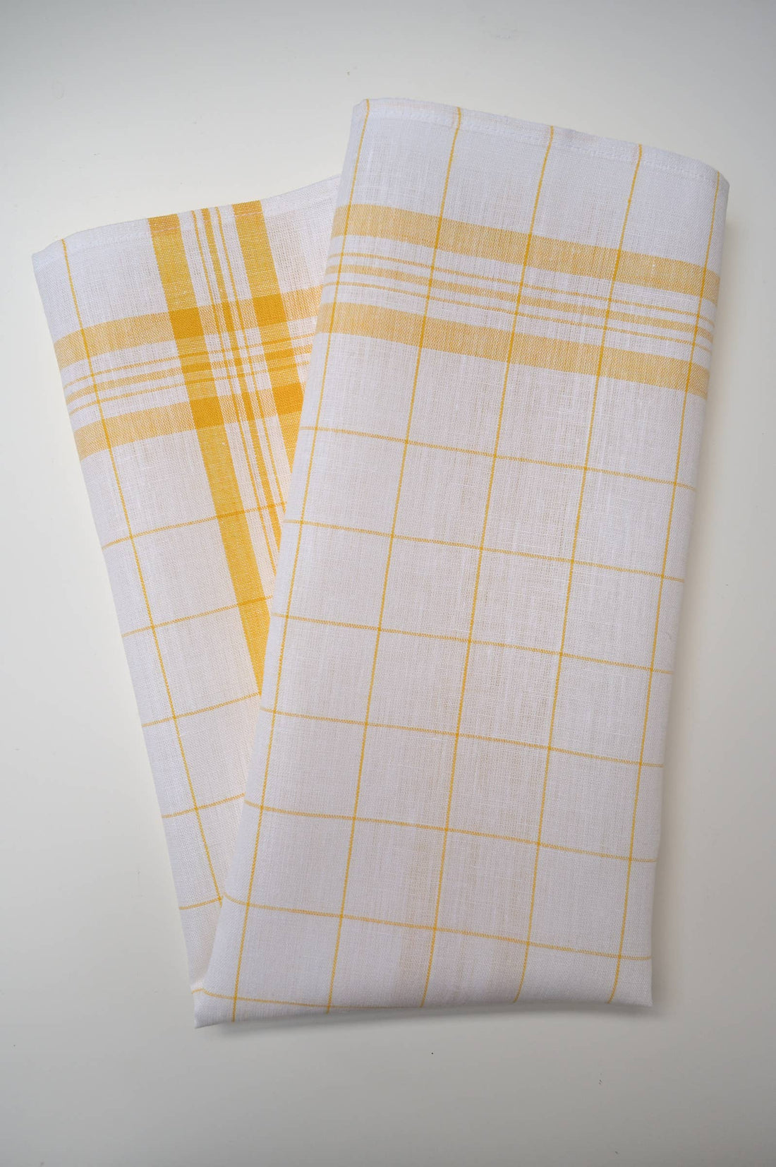 A kitchen towel, white with yellow checkered patterns on a light gray background