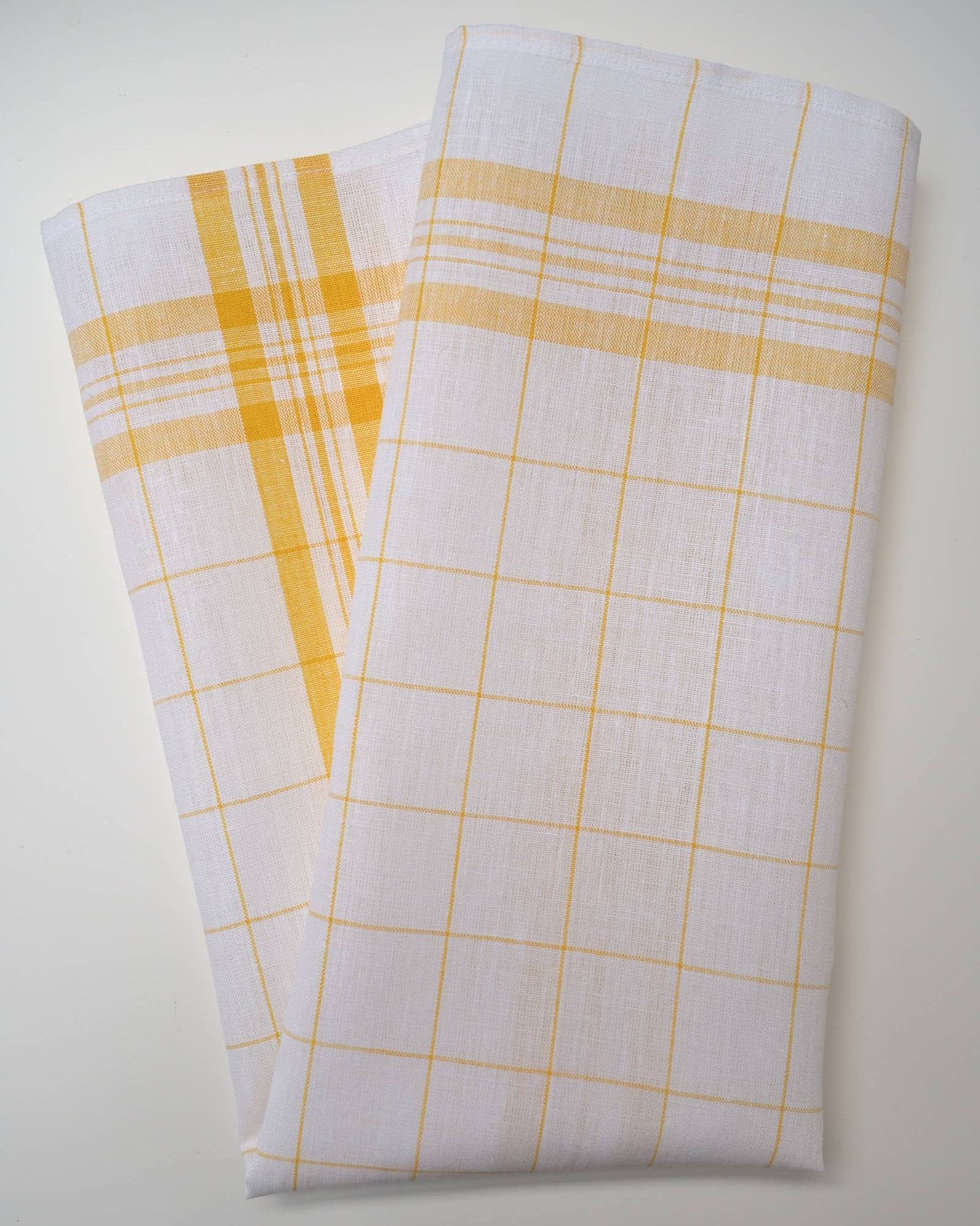 A kitchen towel, white with yellow checkered patterns on a light gray background
