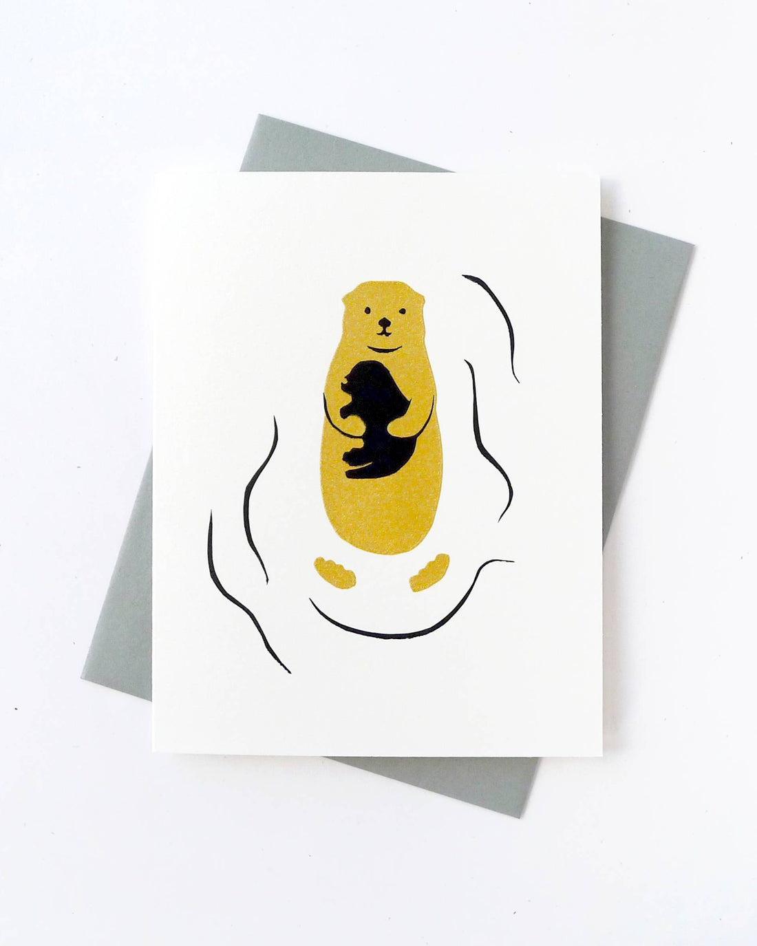 Greeting card with a yellow otter and black silhouette  of a baby otter on its chest on a white background