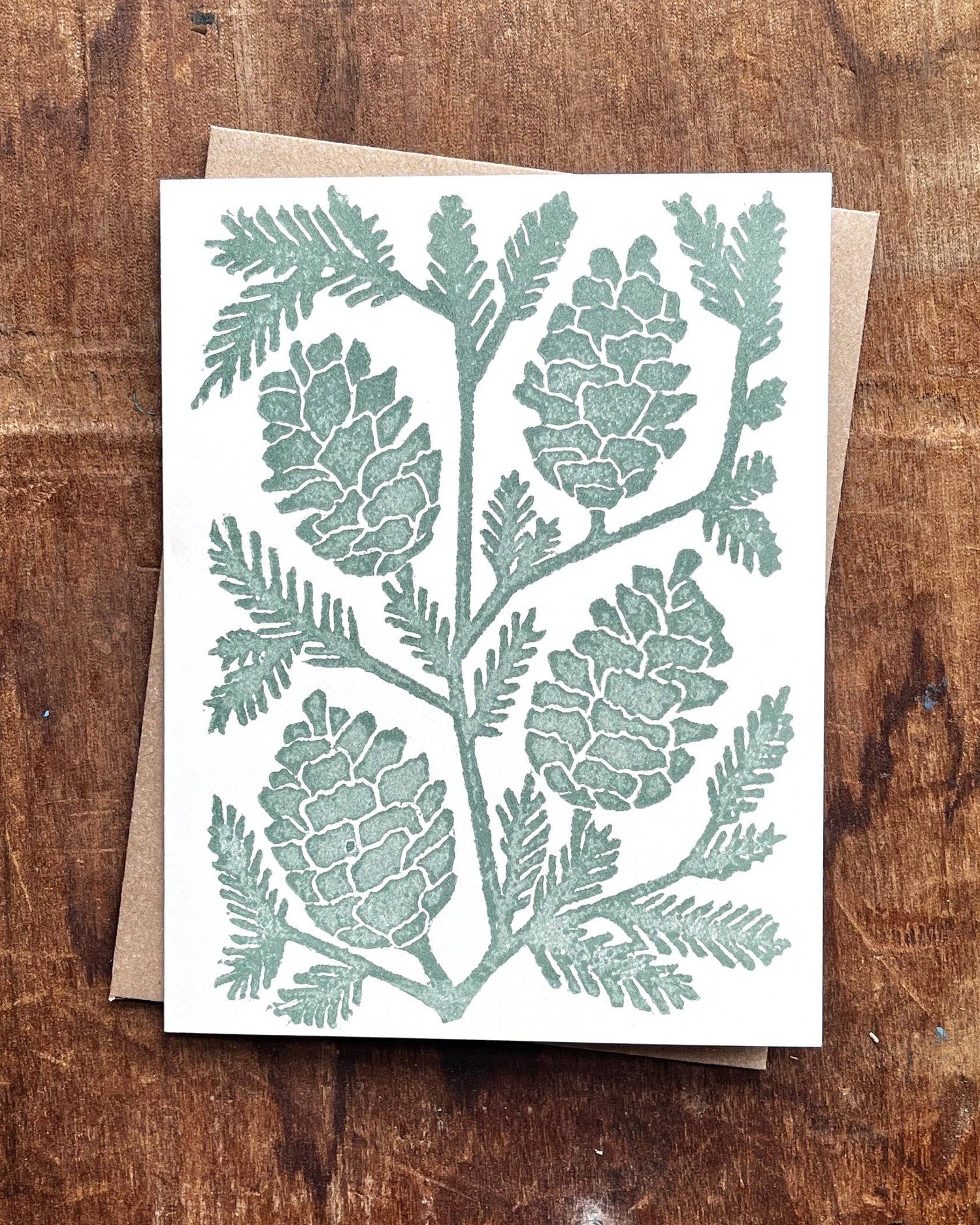 Card with pinecone design on a wooden surface